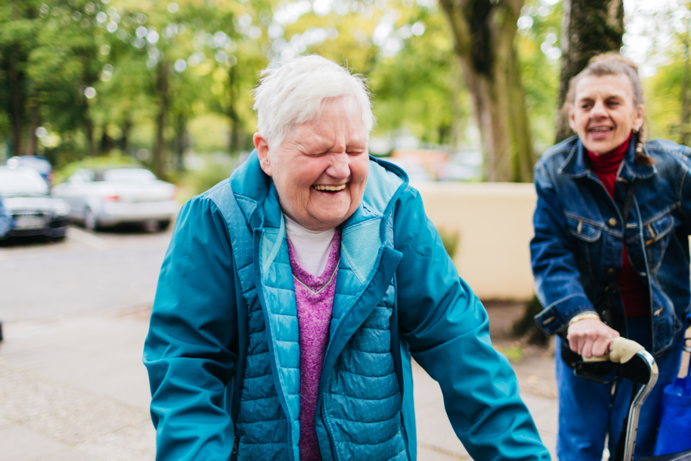Zwei Frauen mit Rollator lachen.