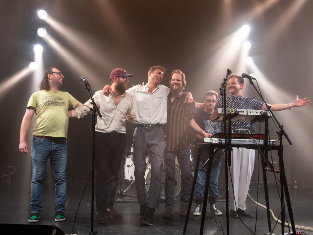 Musiker der Band Station17 lachen aufgereiht auf der Bühne.