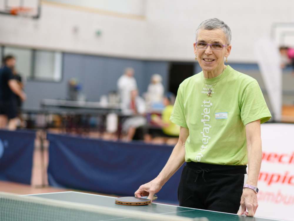 Frau mit grünem T-Shirt beim Tischtennisspielen.