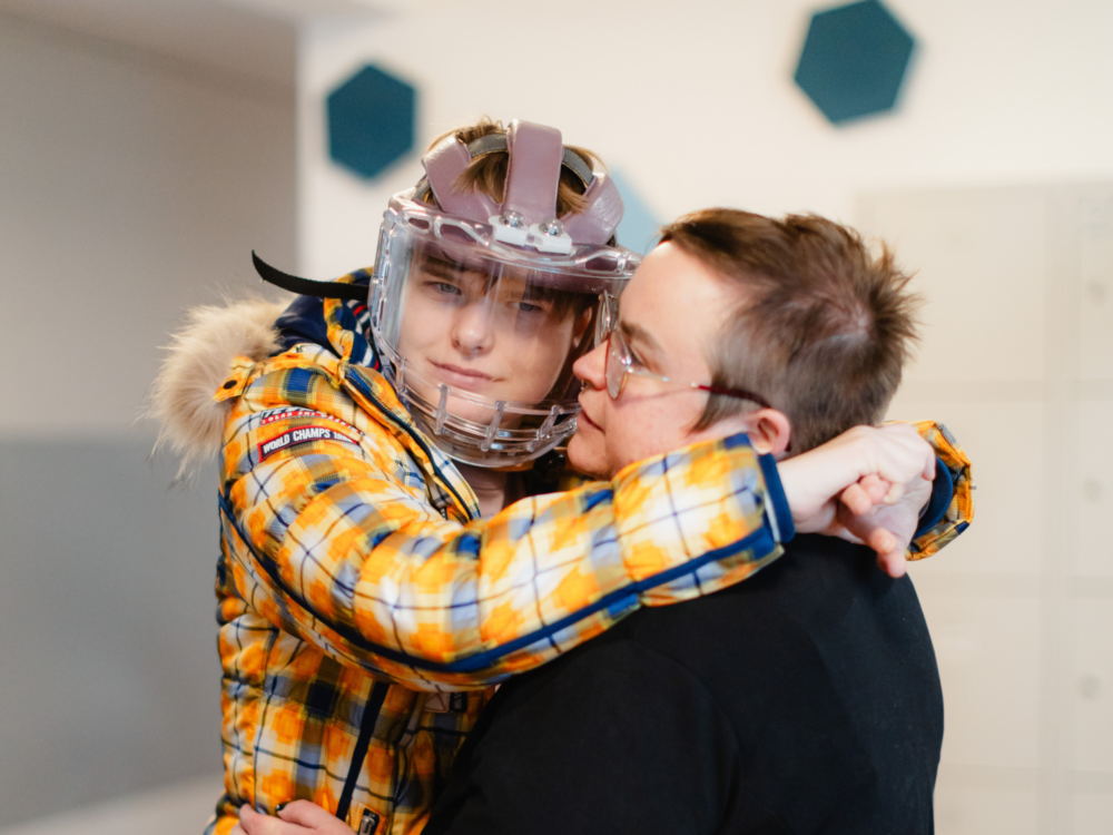 Klient mit Kopfschutz umarmt Sozialpädagogin.