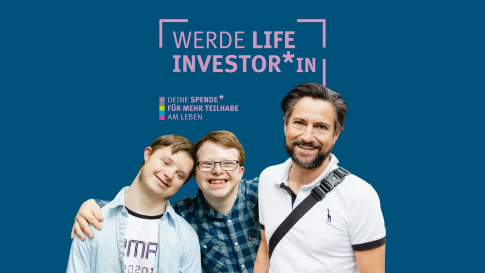 Junge Männer mit Down-Syndrom und Assistenz lächeln. Über ihnen steht der Slogan Werde Life Investor*in