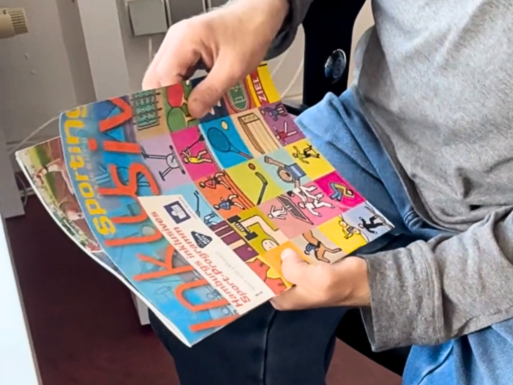 Ein Paar Hände halten Sportmagazin Sporting inklusiv.