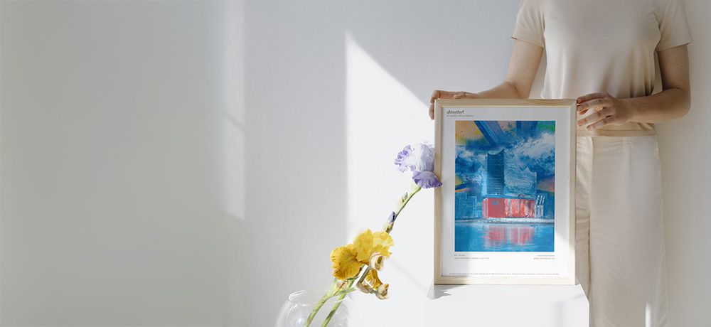 Person hält Bilderrahmen fest. Im Bilderrahmen ist die Elbphilharmonie als Kunstwerk zu sehen.