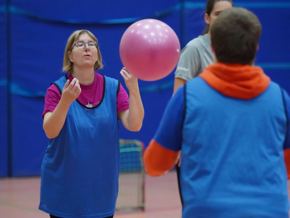 Zwei Sportler*innen werfen sich Ball zu.