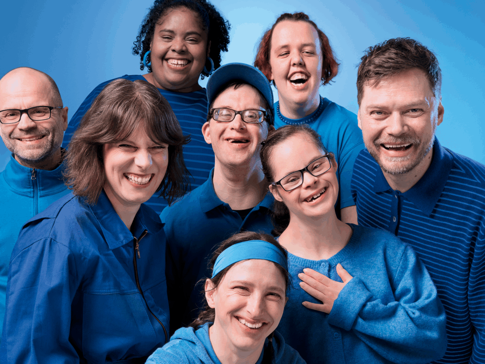 Kampagnen-Motiv: Viele unterschiedliche Menschen mit und ohne Behinderung lachen in die Kamera. Sie alle tragen blaue Kleidung und stehen vor einem blauen Hintergrund.