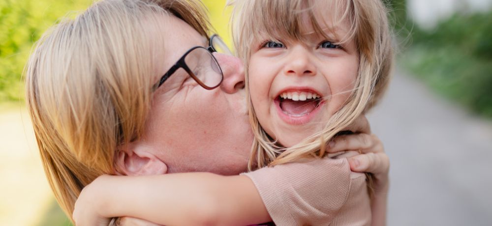 Eine Frau herzt ein freudig lachendes Kind