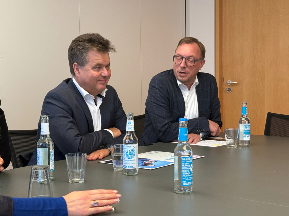 Zwei Männer sitzen an einem Tisch und unterhalten sich.