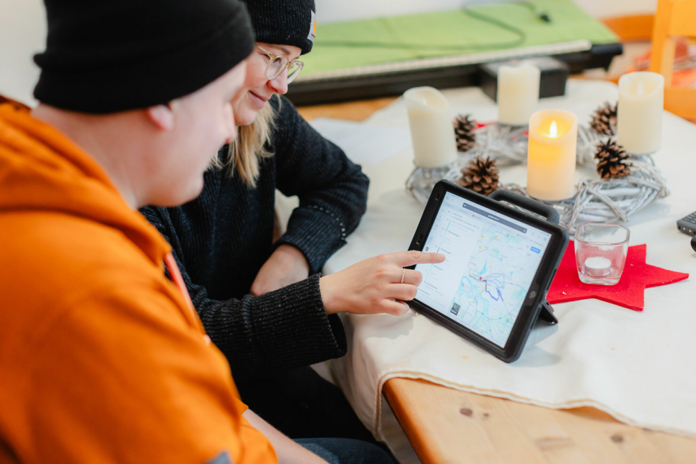 Zwei Menschen schauen zusammen auf ein Tablet. Sie suchen sich eine Wegbeschreibung raus.