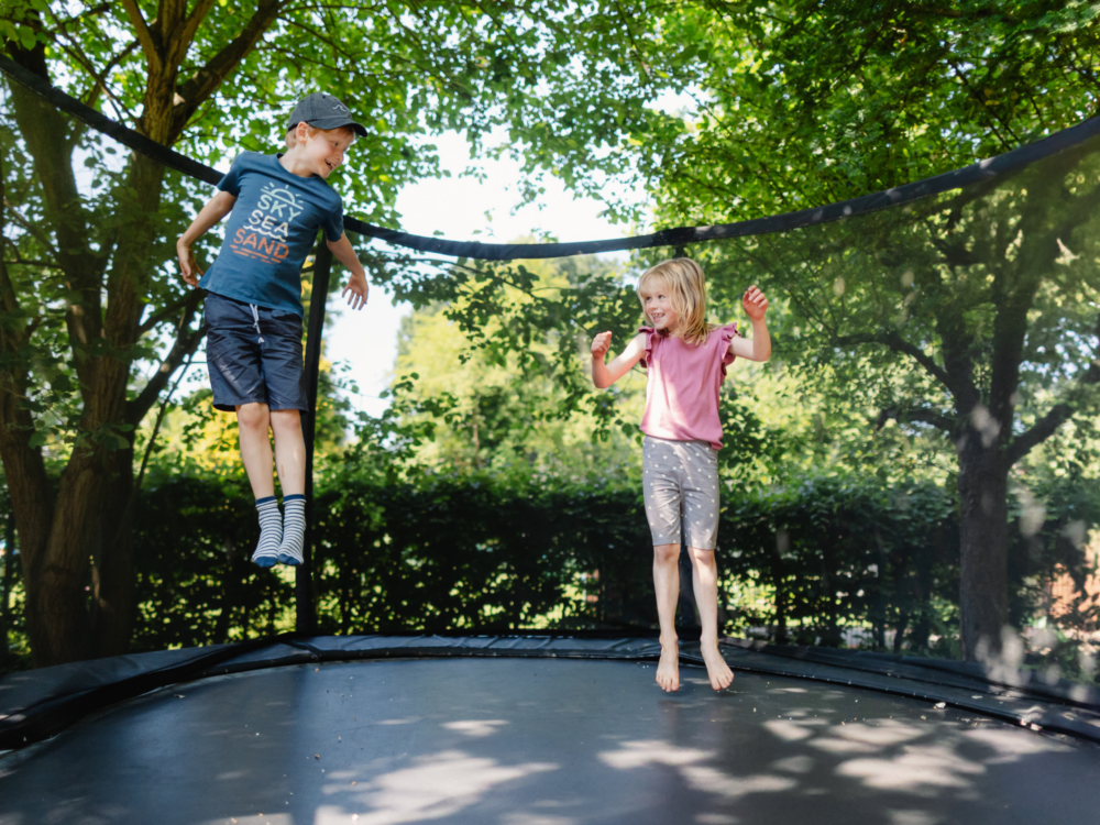 Zwei Kinder springen auf einem Trampolin.