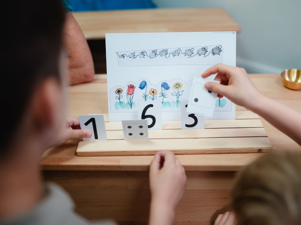 Kinder sortieren Zahlen auf einem Rechenspiel.